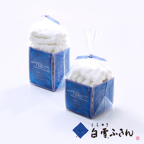 兩個白色毛巾產品，分別裝在透明塑膠袋中，並以藍色緞帶綁住。每個產品皆附有印有藍色波浪圖案和日文說明標籤。
