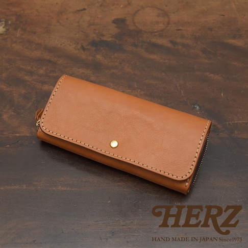 焦糖色皮革長夾，寬口設計，配有金色按扣與拉鍊，縫線精緻，展現職人手作質感。