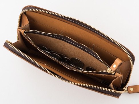 職人手作皮革長夾，主體為棕褐色皮革，內部分隔層清晰，設有拉鍊零錢袋，袋內裝有硬幣，整體線條簡潔，質感樸實。