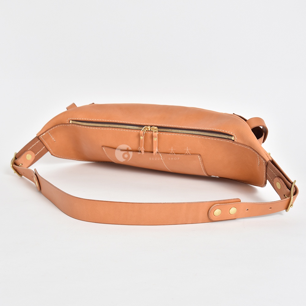 一個棕褐色的皮革斜背包，採用拉鍊開合，肩帶上有金屬釘扣，背景為白色。