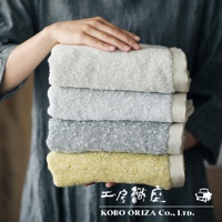 一疊四條SUFFICE 棉麻混紡快乾毛巾，顏色由上至下為淺灰、中灰、深灰和鵝黃。毛巾質地柔軟，邊緣有編織紋理。