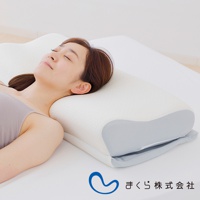 一位女性頭部側臥於白色與淺灰色布料的15度半身枕上，枕頭表面有細緻的紋理，材質看起來柔軟舒適。