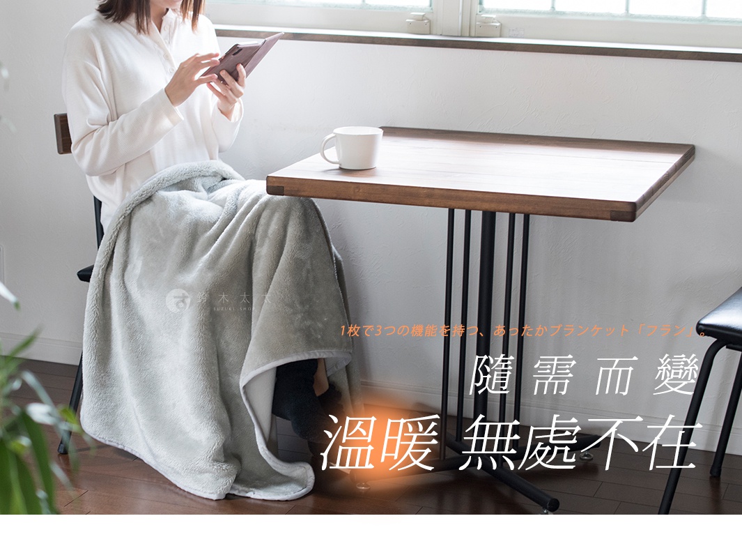 淺灰色絨毛保暖毯，蓋在坐在椅子上的人腿上，毯子觸感柔軟，邊緣有白色滾邊。