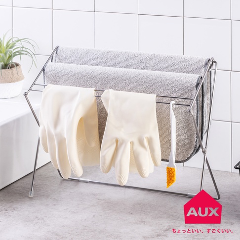 銀色金屬折疊式晾曬架，架上掛有兩雙米白色乳膠手套，上方兩層掛有灰色毛巾，右側掛有一支白色柄橘色刷毛的清潔刷。