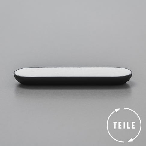 黑色的長方形固體皂，帶有圓潤的邊緣，皂體為白色，置於灰色背景上。