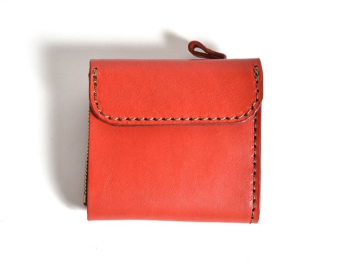 橘紅色皮革方形短夾，帶有縫線細節，左側有拉鍊，上方有一個皮革提帶。