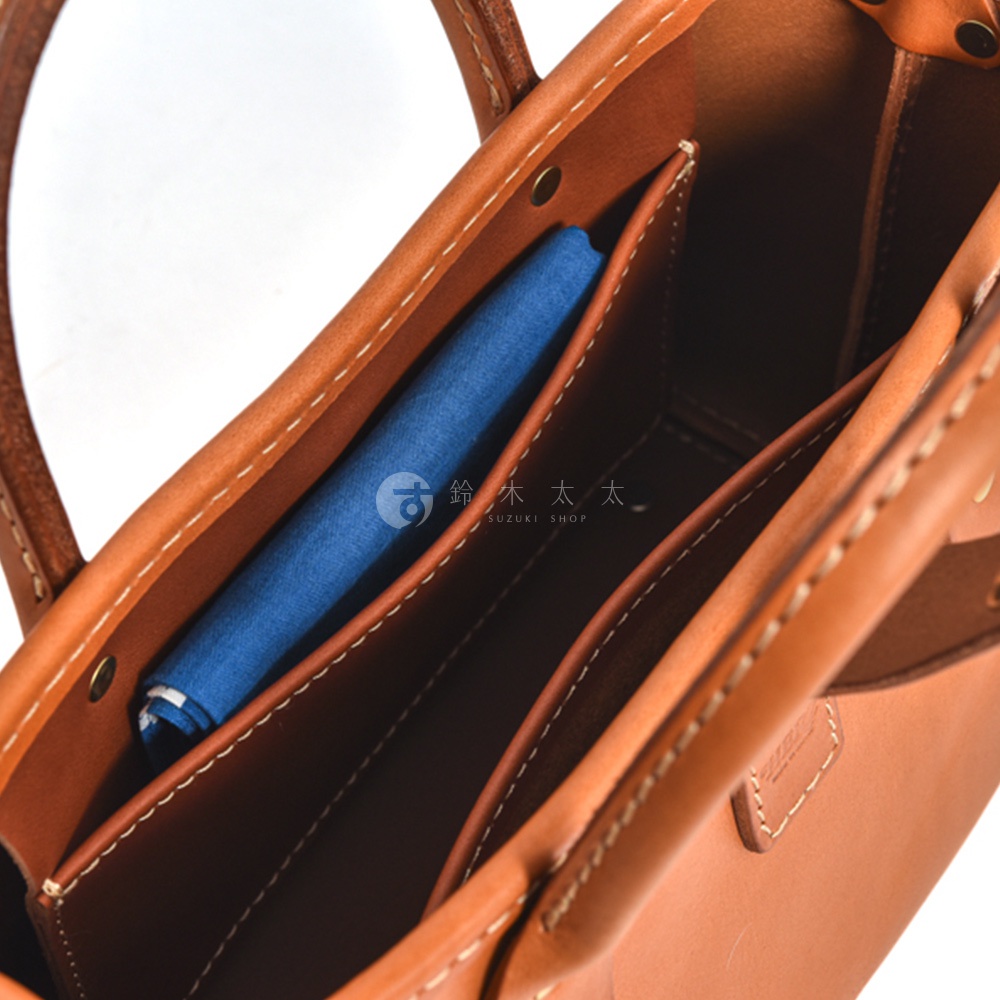 職人手作皮革迷你托特包 T-11，以棕褐色皮革製成，包內有藍色布料內襯和多個隔層，展現精緻車縫工藝。