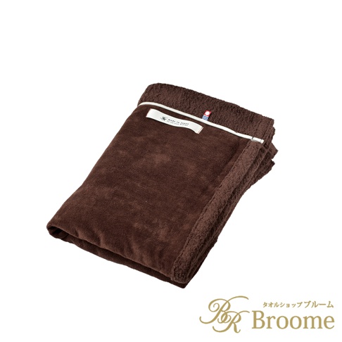 一件深棕色的日本製造膝蓋毯，上面有一條白色滾邊和一個標籤。