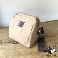 石洗帆布散步包，淺米色，方形包體，附有深棕色織帶，包面中央有方形皮標，上面印有動物圖案，右下角有狗和行李箱的剪影圖案，並有日文文字。