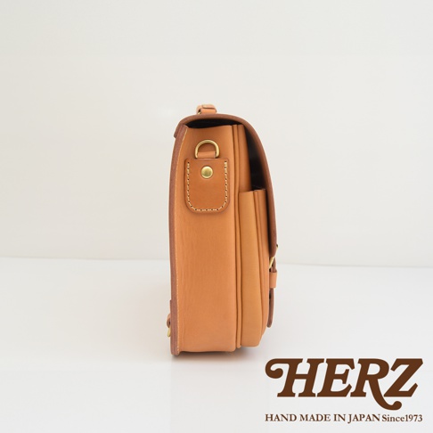 職人手作皮革極簡風三用商務公事包，採用天然牛皮，呈現溫潤的淺棕色調，側邊設有金屬釦環與可調整的皮質揹帶，整體設計簡潔實用。