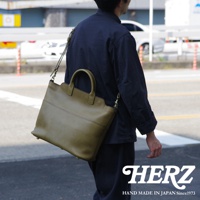 職人手作皮革大容量兩用托特包，採用橄欖綠皮革製成，設有雙提把與可拆卸肩背帶，包身有縫線裝飾，設計簡約大方。