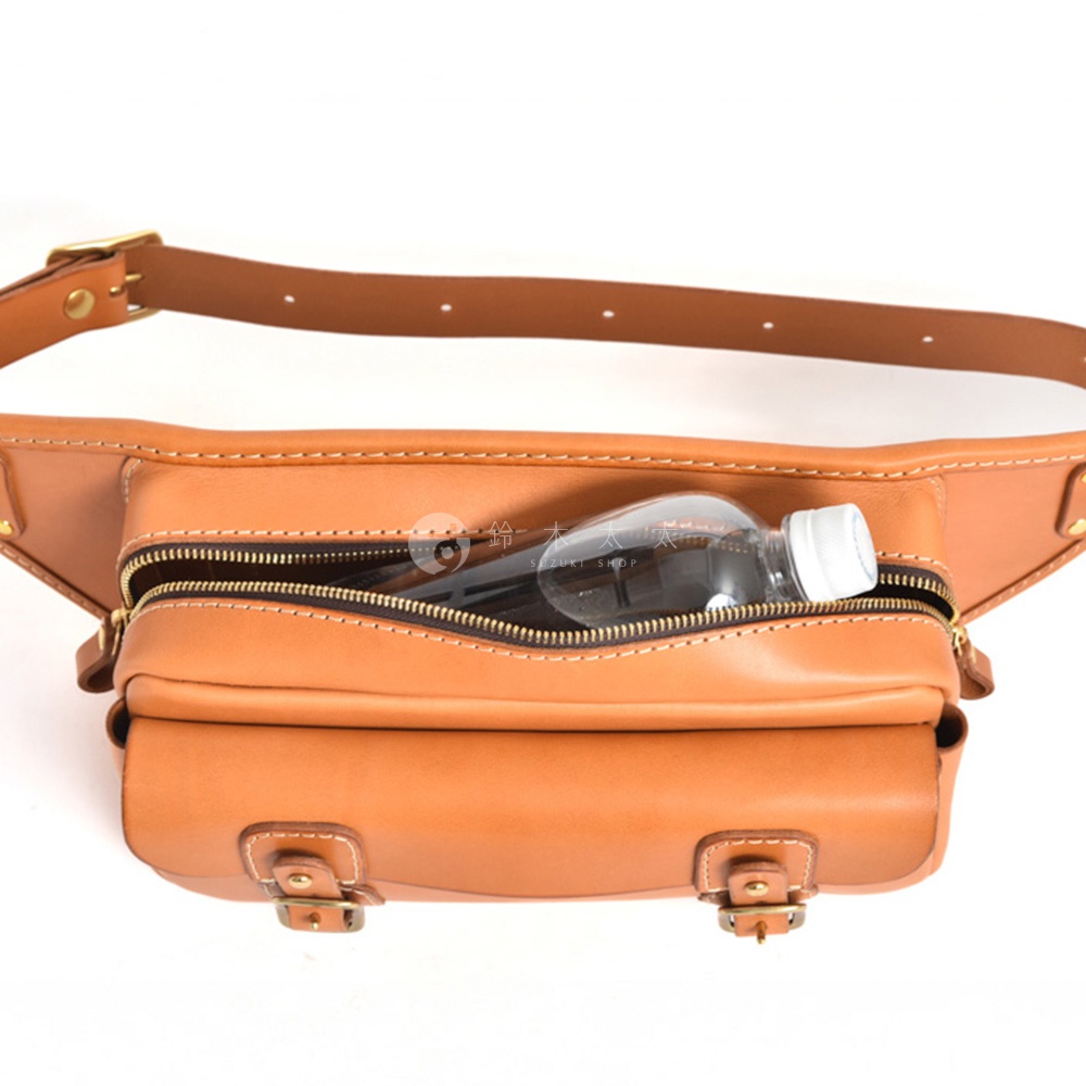 棕色皮革騎士隨身斜背包，設有拉鍊主隔層，內有一瓶透明塑膠水瓶。包包前方有翻蓋式小口袋，以金屬扣固定。