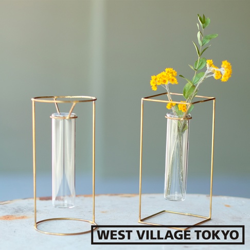 黃銅四角框架搭配玻璃試管花器，一個內有試管，另一個內有黃色小花束與綠葉。