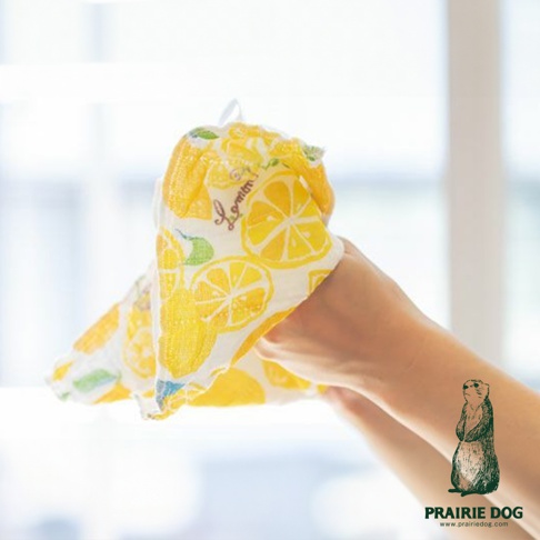 五層紗質地的擦拭巾，印有黃色檸檬圖案，由雙手拿著，背景模糊，有品牌標誌。