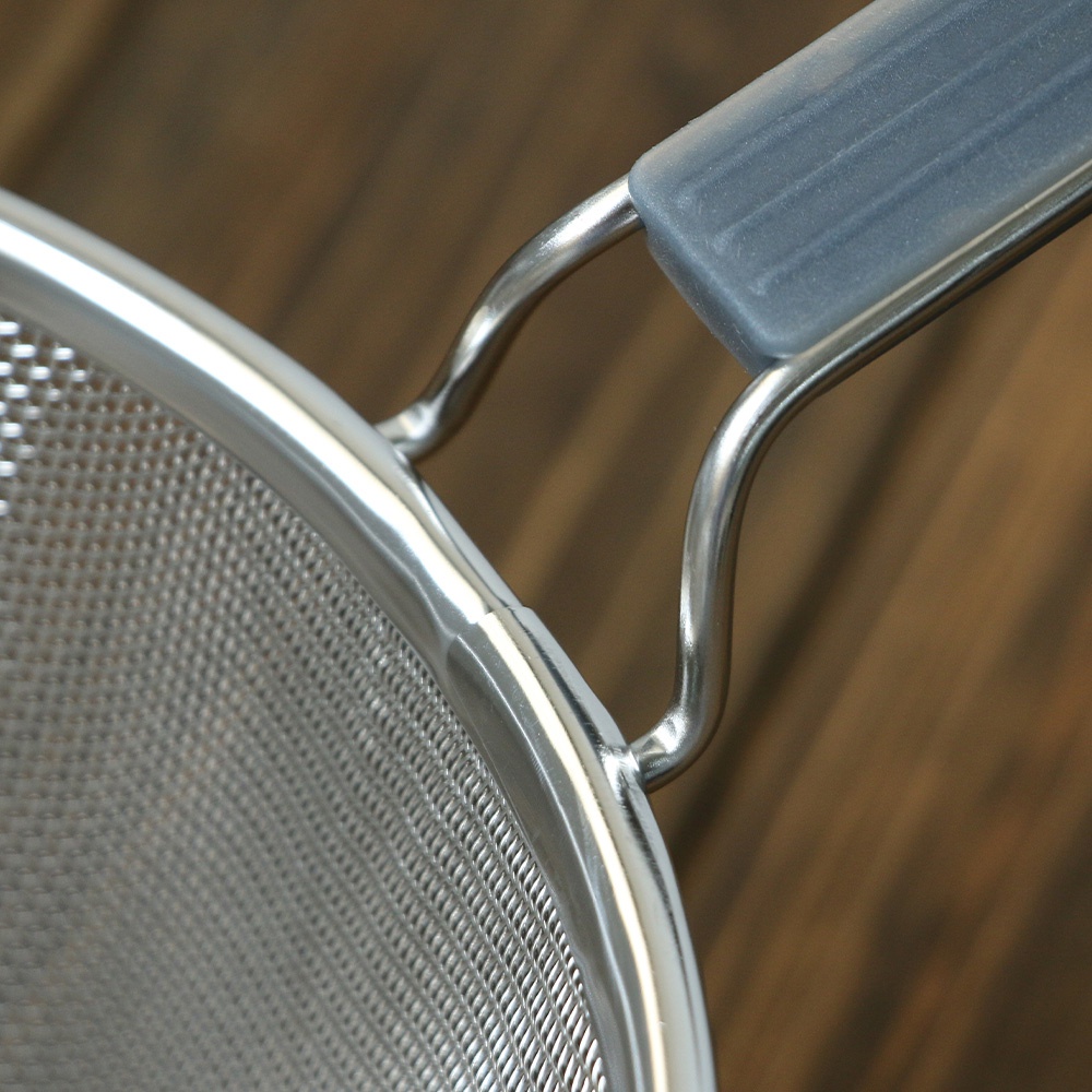 不鏽鋼濾網，帶有灰色矽膠握柄，網孔細密，邊緣光滑。