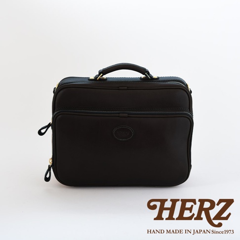 黑色皮革兩用商務公事包，方形設計，頂部有提把，正面有拉鍊夾層，側面有拉鍊開口，中央有品牌標誌。