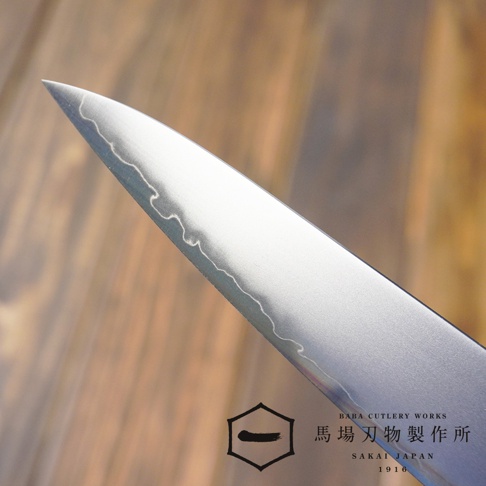 [景清] Chromax鋼水果刀，15公分刀刃，表面有獨特的波浪紋理，呈現金屬光澤，搭配木質紋理背景。