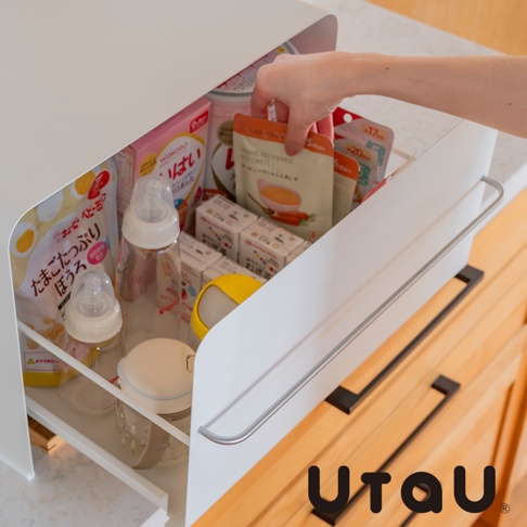 UtaU 抽屜式萬用收納櫃，展示嬰幼兒食品、奶瓶及其他小物，右側有金屬掛桿，上方可見手部正在拿取包裝食品。