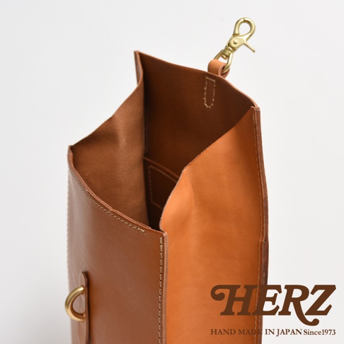 職人手作皮革紙袋風後背包，淺棕色皮革，內部有隔層，頂部有黃銅色掛鉤和皮革提把。