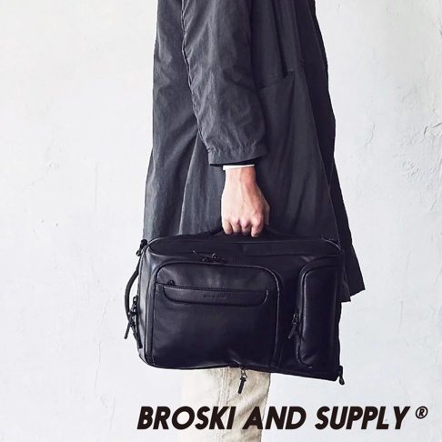 黑色防水真皮革手提後背包，具有多個拉鍊隔層和手提帶，由單手持握。