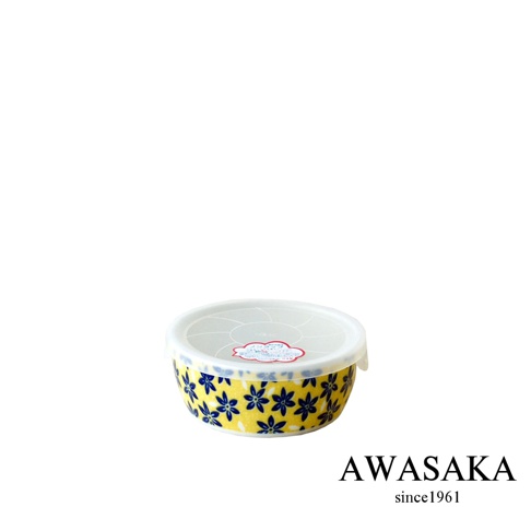 一個帶有黃色底色和藍色小花圖案的圓形陶瓷保鮮碗，碗上蓋著一個透明的白色塑膠蓋。