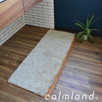 淺米色長條狀、毛絨觸感的地墊，鋪設在木紋地板上，一側有棕色邊緣。