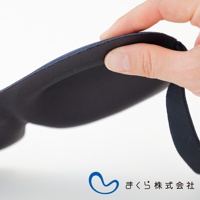 手指輕壓深藍色舒眠眼罩，展現其柔軟的內部填充材質，邊緣有彈性綁帶。