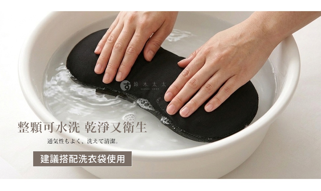 雙手正在將一個黑色豌豆形狀的靠枕按壓浸泡在白色臉盆的水中，展現出產品整顆可水洗的清潔特性，並建議搭配洗衣袋使用。