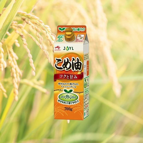 米糠玄米油 700g 產品包裝，以黃色和白色為主，印有日文說明及稻穗圖案，背景為模糊的稻田景觀。
