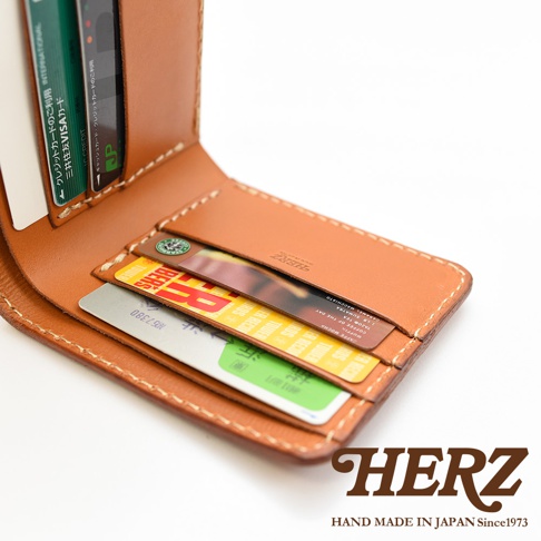 職人手作皮革二折橫式卡片紙鈔小短夾，採用天然皮革材質，呈現經典棕色調。夾內可見多張卡片，包括信用卡與其他識別卡。車縫線清晰，展現細緻工藝。