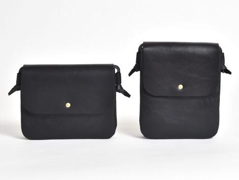 兩款黑色皮革橫式隨行袋，設計簡約，附有翻蓋和金色按扣。