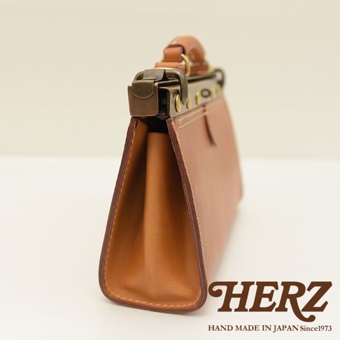 職人手作皮革復古口金兩用手提包，採用棕色皮革，側面展示包身輪廓和復古金屬鎖扣，手工縫線清晰可見。