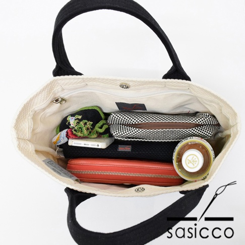 三河木綿刺子織OBI迷你托特包，內部裝有手機、錢包、化妝包及一個圓形罐狀物品。托特包為米白色帆布材質，提把為黑色。