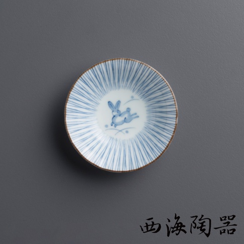 一個圓形陶瓷小碟，碟面飾有藍色細條紋，中央繪有一隻藍色兔子圖案。