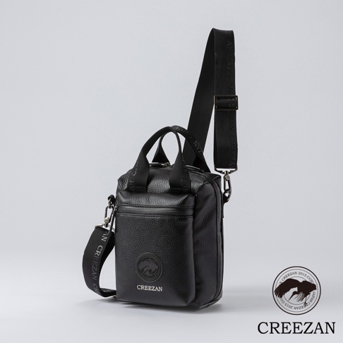 黑色皮革方形側背包，有兩個提把和一條可調式肩帶，肩帶上印有品牌名稱。包包前方有一個拉鍊口袋，上面有品牌標誌。