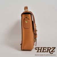 職人手作的歐風皮革三用學生包，展現自然皮革紋理與金屬釦環細節，側邊呈現簡潔的箱型結構。