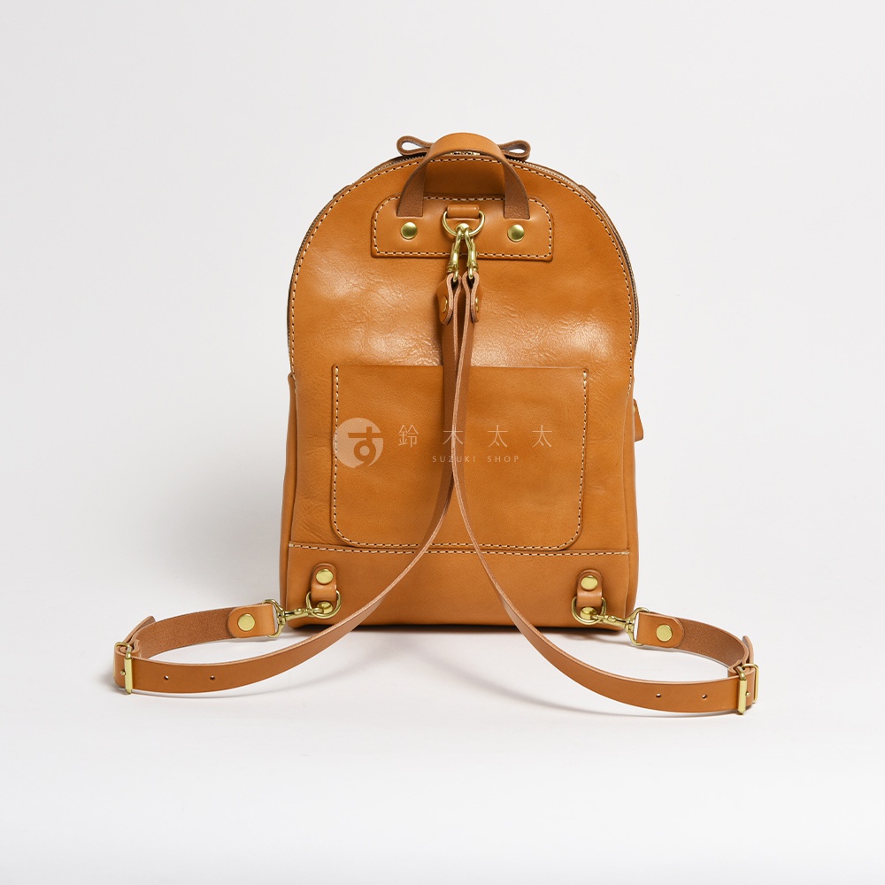 職人手作皮革大開口圓角後背包，呈現自然棕色調，材質為光滑皮革，設計有前置口袋、雙肩帶扣環及頂部提把。