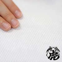 手指觸碰白色紋理布料，右下角有黑色虎頭圖案印記。