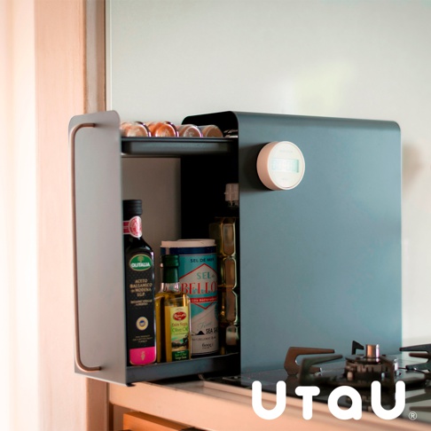 深灰色金屬材質的抽屜式收納櫃，內部擺放著橄欖油、醋、鹽罐及其他調味料，櫃門一側有圓形白色計時器，整體置於廚房爐灶上方。