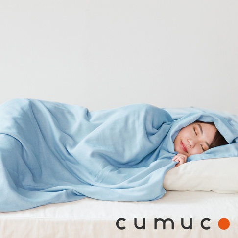 一位女子在床上蓋著淡藍色的四層紗輕暖舒柔四季毯，毯子材質輕盈柔軟，呈現出細緻的紋理。