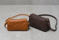 兩款職人手作皮革Organ輕巧拉鍊單肩包，一款為棕色皮革，另一款為深棕色皮革，均配有金色拉鍊和可調節皮革肩帶。