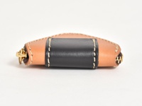 職人手作皮革三角飯糰造型零錢包，採用原色皮革與黑色皮革拼接，搭配金屬拉鍊與米白色縫線，呈現獨特質感。