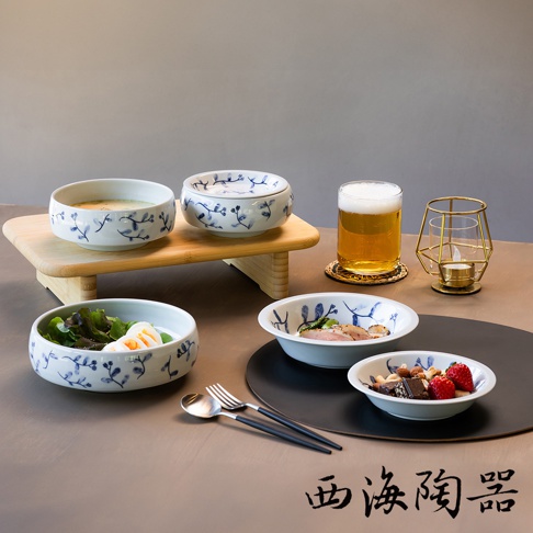 波佐見燒藍花紋四件式深碟盤組，包含盛有湯、沙拉和雞肉的白色陶瓷盤，以及裝有堅果和草莓的淺盤，盤身飾有藍色花卉圖案，搭配木製托盤、啤酒杯和燭台。