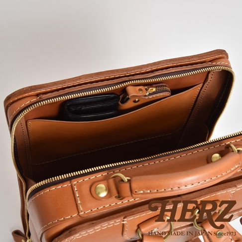 職人手作皮革商務電腦後背包 R-25，棕色皮革材質，展示內部收納空間，包含一個拉鍊小袋和一個開放式隔層，可放置錢包。