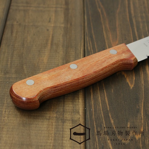 [堺一次] 不鏽鋼麵包刀，茶色木質手柄，配有三個銀色鉚釘，刀刃部分可見鋸齒狀切割邊緣，整體置於深色木紋背景上。