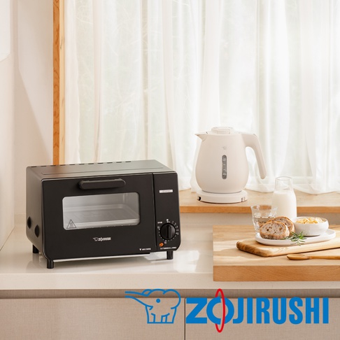 黑色電烤箱，配有玻璃門、銀色把手和黑色旋鈕。旁邊有一個白色電熱水壺、一杯水、兩片麵包和一碗麥片。