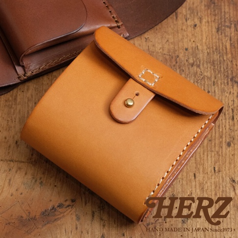 職人手作皮革原子釦型二折式短夾，呈現自然 tan 色調，皮革材質，帶有精緻縫線與金屬原子釦。