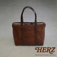 棕色皮革製成的職人手作Organ肩背拉鍊托特包，帶有雙提把和金色拉鍊，包身中央有縫線裝飾，質感樸實。