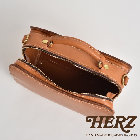 棕色皮革兩用方形單肩包，帶有拉鍊開合、提把和金屬扣件，展現職人手作質感。