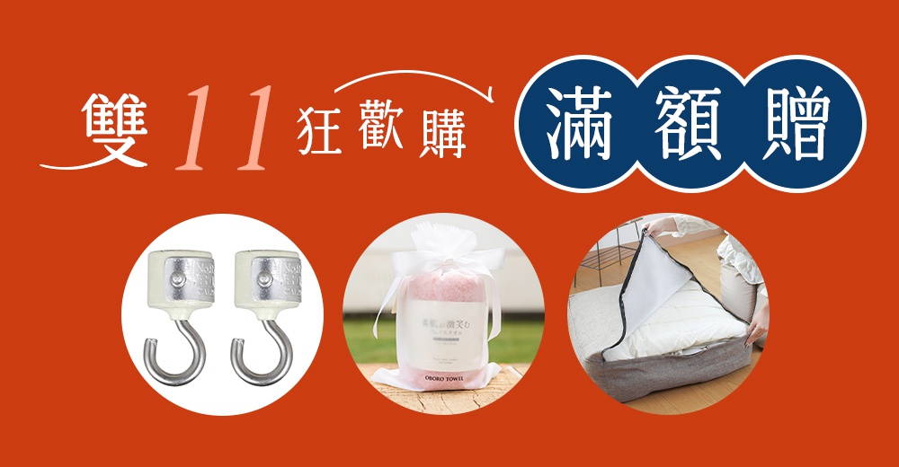 一張橘色背景的雙十一活動促銷圖，上方橫排標題為雙十一狂歡購以及滿額贈三個大字，下方並排展示三項贈品，分別是兩個金屬掛鉤、一個用白色緞帶包裝的粉色毛巾禮盒，以及一個正被打開的灰色布質收納袋。